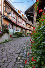 Fototapeta na wymiar Alley with old half-timbered houses decorated with flowers. Eguisheim, France, Europe