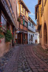 Fototapeta na wymiar Alley with old half-timbered houses decorated with flowers. Eguisheim, France, Europe