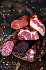 Different kind of smoked meat and spices on wooden board