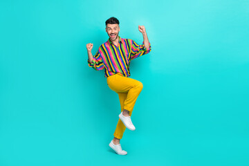 Fototapeta na wymiar Full length photo of good mood handsome man brunet hair dressed striped shirt dancing clench fists isolated on turquoise color background