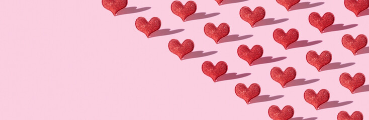 Pattern with red glitter heart shape on pink background with hard shadow. Valentines day minimalistic symbol love. Banner