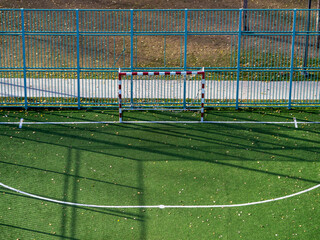 Obraz premium The football field, markings and fences are illuminated by the sun. Frontal view of the football goal from above.