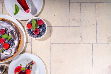 Homemade cheesecake with chocolate and berry. Sweet cottage cheese cake pie with fresh and chocolate topping, classic dessert om beige tiled table copy space