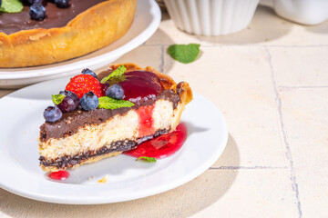 Homemade cheesecake with chocolate and berry. Sweet cottage cheese cake pie with fresh and chocolate topping, classic dessert om beige tiled table copy space