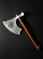 Antique medieval old axe with wooden handle isolated on black background.