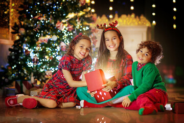 Fototapeta na wymiar Kids at Christmas tree. Children open presents