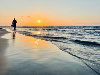 Spacer brzegiem morza przy zachodzie słońca