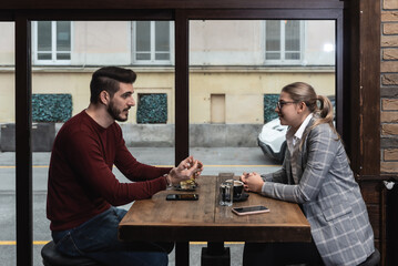 Confident owner of cafe interviewing young specialist. Manager of cafeteria or coffee shop job interview with young male bartender barista or waiter applied for work in the restaurant. Employee hiring