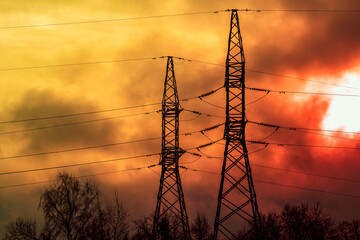 Electric power transmission lines in a dark smoke and fire light.