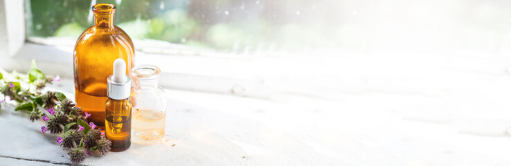 Banner Flowers Wild basil , Clinopodium vulgare or Satureja vulgaris close-up near cosmetic bottles with a pipette and oils made from medicinal herbs.