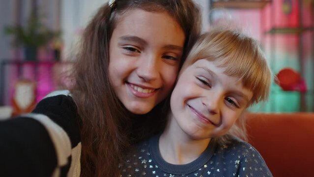 POV portrait of happy calm teenage and little sisters child kids smiling friendly, glad expression looking away dreaming resting, relaxation. Female siblings children or best friends at home playroom