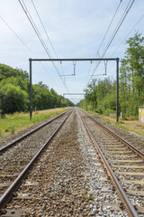 Fototapeta premium electric wired railway tracks landscape perspective green trees blue sky whiye clouds