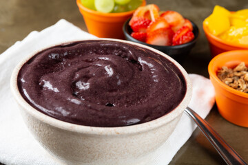 Açaí on a bowl with strawberry, mango and grape on colorful bowls over a stone background