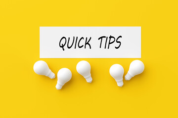The word quick tips on white paper surrounded with light bulbs. Useful advice, information or ideas...