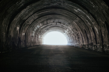 Old underground road tunnel inside mountain. Light at the end of tunnel