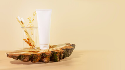 Organic oral care products set. Eco friendly still life with bio toothpaste, toothbrushes in a glass jar on wooden podium with copy space. Natural teeth hygiene concept. Mockup for toothpaste