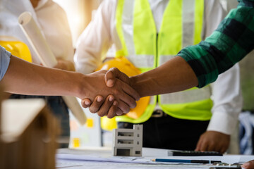 Fototapeta na wymiar Construction workers, architects and engineers shake hands while working for teamwork and cooperation after completing an agreement in an office facility, successful cooperation concept.