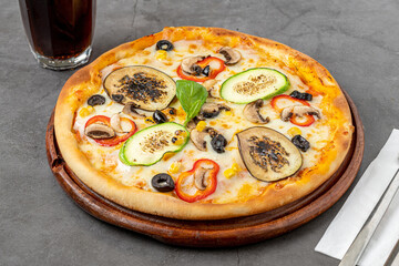 Vegetarian pizza with eggplant, zucchini and mushrooms on dark stone table