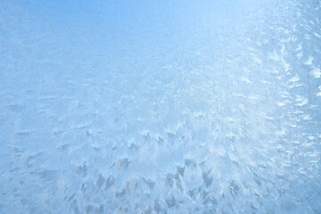 snow frost in the form of natural patterns on the window pane against the background of the morning sky