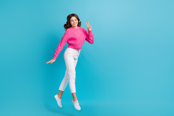 Fototapeta na wymiar Full length photo of shinny friendly lady wear pink walking showing v-sign empty space jumping high isolated blue color background
