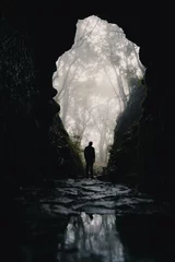 Fotobehang a man is standing in a dark cave on madeira © patsch.1