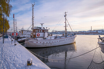 Naklejka premium Old fishing boats at the pier Norr Mälarstrand a pale snowy winter day in Stockholm
