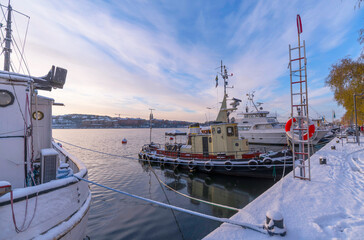 Old tug boat at the pier Norr M&auml;larstrand a pale snowy winter day in Stockholm
