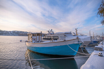 Fototapeta premium Old fishing boats at the pier Norr Mälarstrand a pale snowy winter day in Stockholm