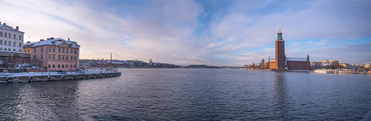 Fototapeta premium Down town bay view the Town City Hall hotels, offices and moored commuting boats a pale snowy winter day in Stockholm