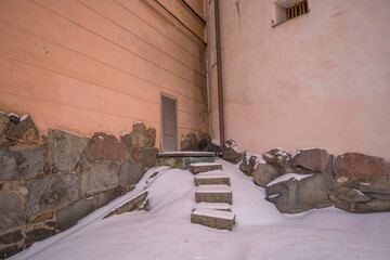 Stone stairs and foundation of old yellow court houses on the island Riddarholmen a pale snowy winter day in Stockholm