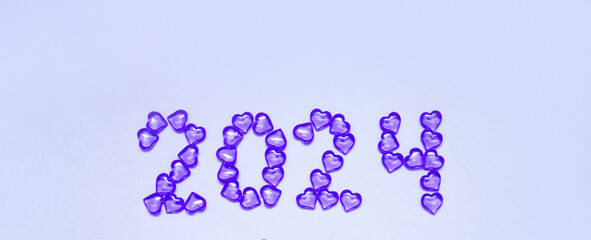 New Year 2023 inscription from glass hearts on a violet background. Pantone color 2023. Idea and creativity. Valentine's Day. Christmas with loved ones. Horizontally, banner. High quality photo
