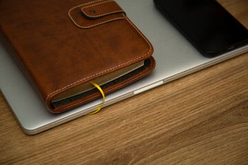 Business set, leather notebook, laptop and smartphone on a wooden table