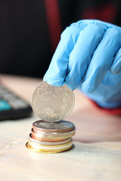 A Silver Australian Coin Held On A Pile Of Coins By A Person Wearing Blue Gloves