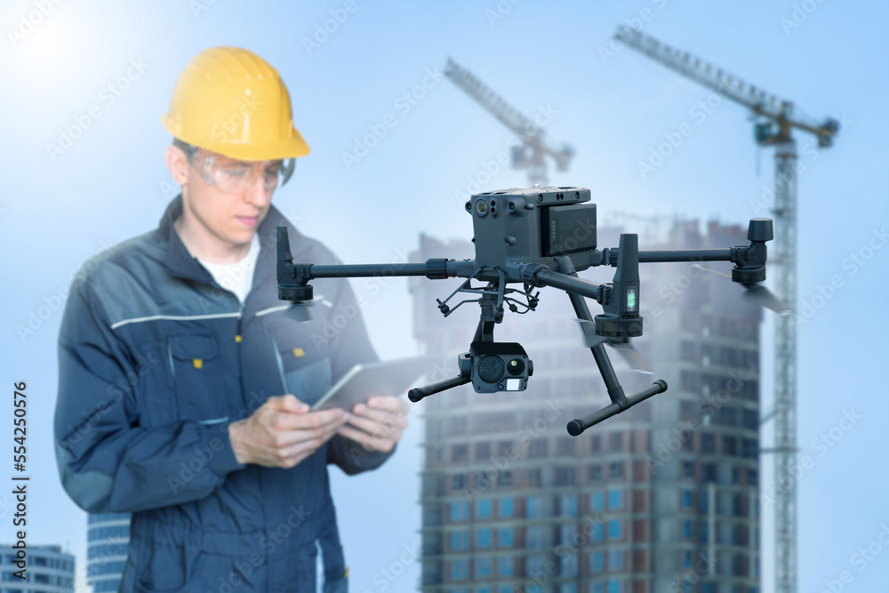 Poster engineer with digital tablet controls drone on a construction site
