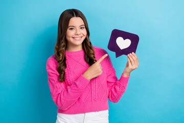 Photo of funny excited teen schoolgirl wavy hair wear pink jumper finger direct purple paper love symbol popularity isolated on blue color background