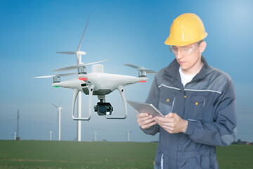 Engineer with tablet computer controls drone on a background of wind turbines