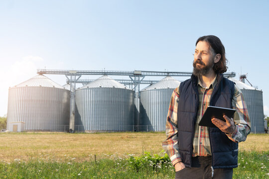 Farmer with digital tablet in front of agricultural silo