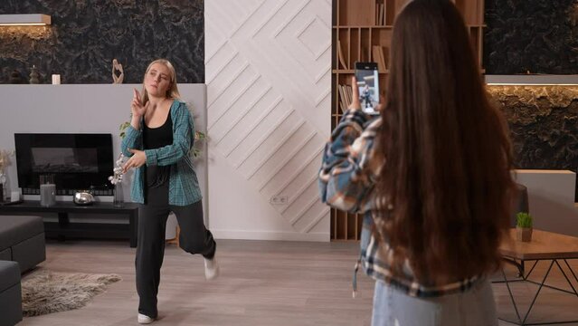 Wide shot of two girls filming video for social media. Beautiful female teen dancing hip hop, while her friend shooting dance on smartphone camera. 4k High quality footage