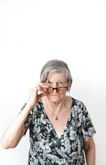 Skeptical woman looking at camera while peering over her eye glasses. White isolated background.