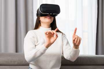 Happy young woman using a virtual reality headset and pushing invisible buttons.