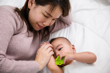 Mom and baby newborn in diaper playing together, Parent and little kid relaxing on bed, Asian mother lull to sleep with her baby in bed on bedroom, Happy family in house