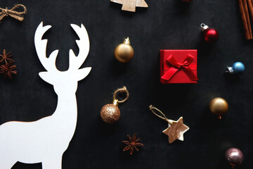 Small presents, various Christmas ornaments and deer figurine on dark background. Top view.