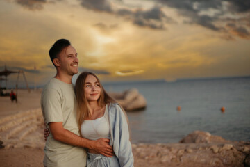 couple in love on the shore of the beach of the sea walks on a date. Young family couple in summer clothes on a honeymoon trip.