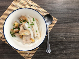 Chinese roll noodle soup In a white cup, on a bamboo floor, on a dark brown table
