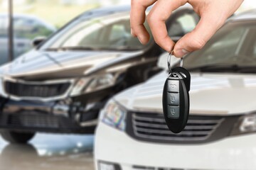 Hand hold a new car key on car background