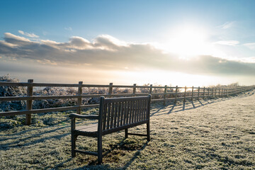 Fototapeta na wymiar Isolated wooden park bench seen on a cliff overlooking a cold North Sea during early morning.