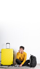 Worried guy traveler wear sweater holding suitcase, with hand near mouth, gnawing nails, feels uncertain, stressed. Confused man with frighten or panic gesture, isolated on white background.