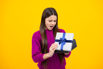 Child with gift present box on isolated background. Presents for birthday, Valentines day, New Year or Christmas. Angry teenager girl, upset and unhappy negative emotion.