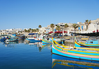 Fototapeta na wymiar Colorful fishing boats in port of european Marsaxlokk town in Malta