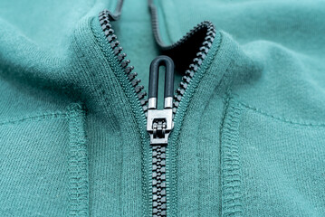 Close-up of the zipper on the green clothing. Zipper with lock. Fabric with zipper